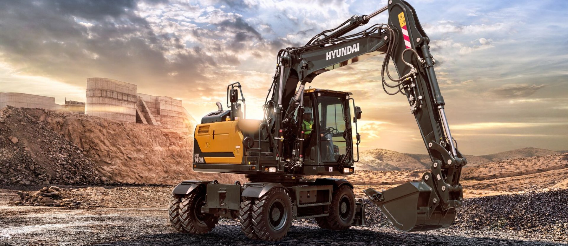 HD Hyundai HW140A sur un chantier de construction au coucher du soleil