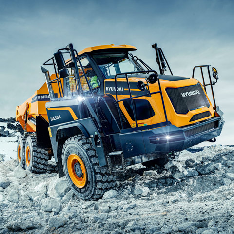Hyundai articulated dump truck (ADT) driving up hill on snowy and rugged terrain.