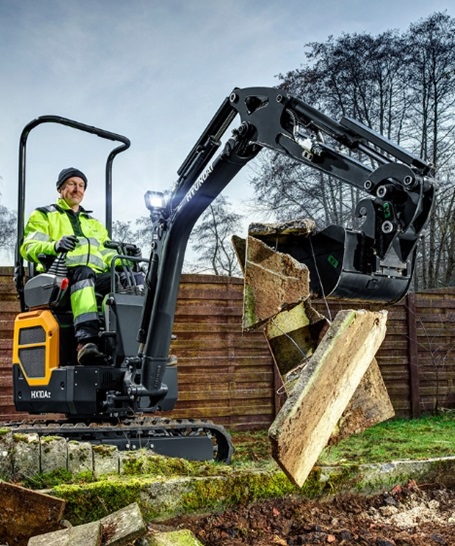 Hyundai HX10A Z mini excavator picking up scrap in a back garden