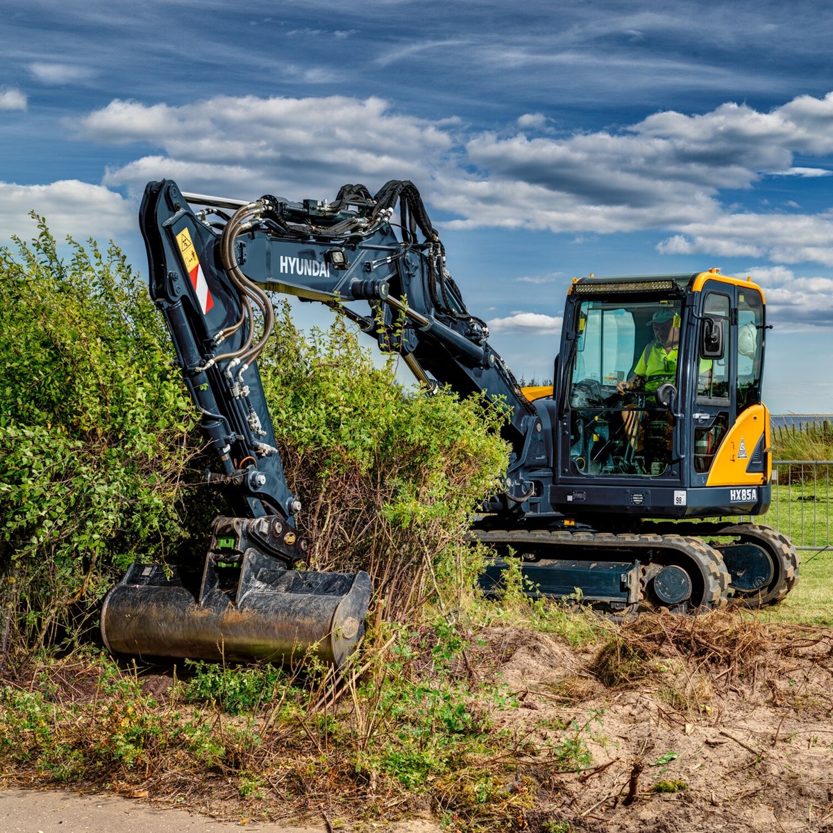 HD Hyundai HX85A compacte graafmachine maakt een veld vrij