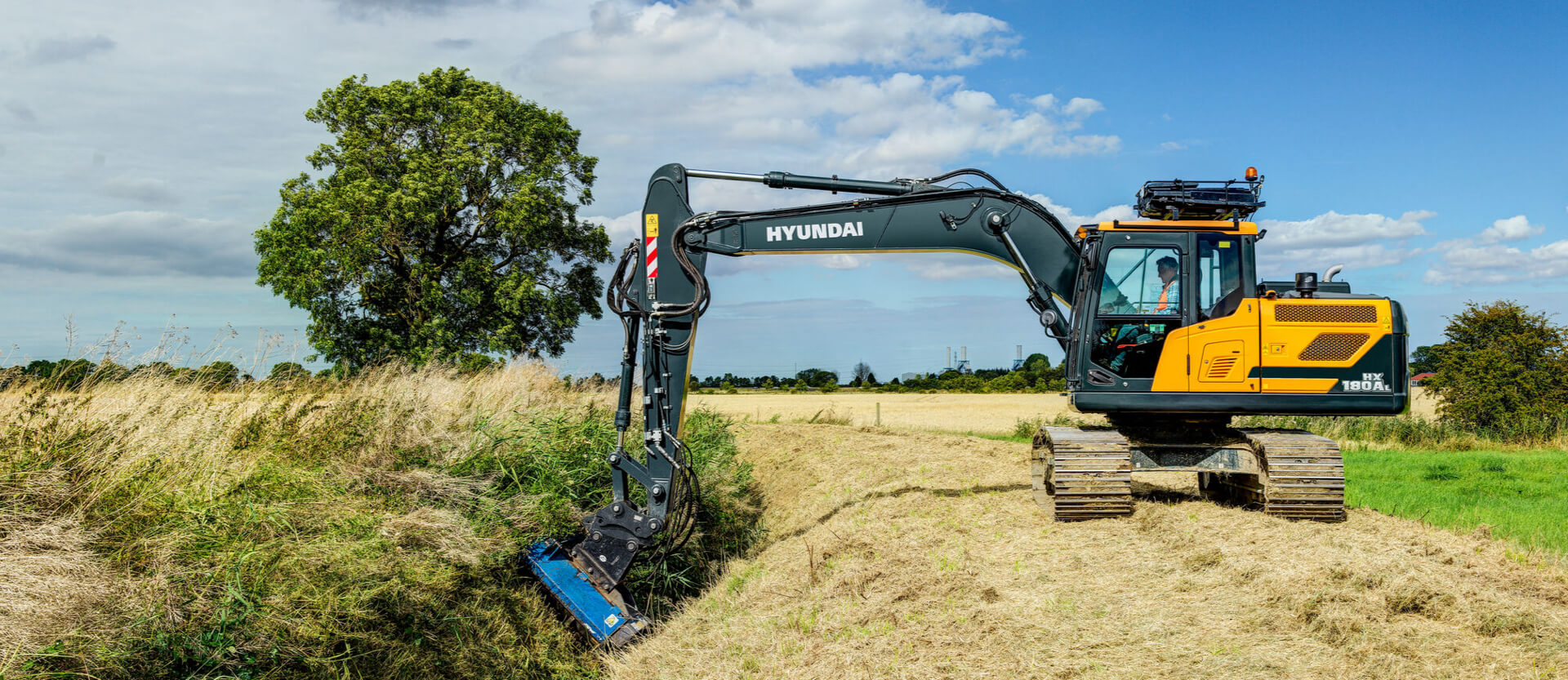 HD Hyundai HX180A L rupsgraafmachine op een veld met gebruik van de maaiertoepassing