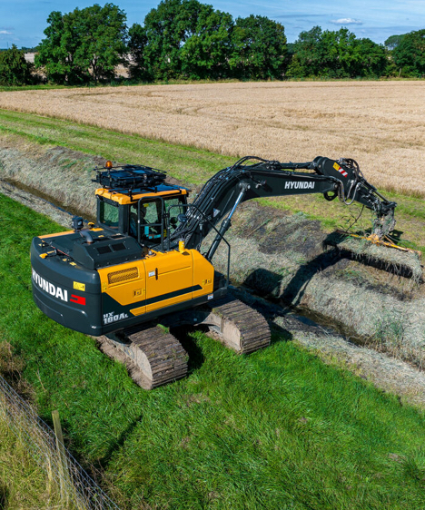 HD Hyundai HX180A L rupsgraafmachine op een veld met gebruik van de maaiertoepassing