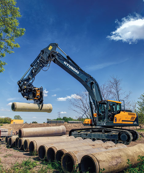 The HX330A L using the grabber attachment to pick up a large pipe