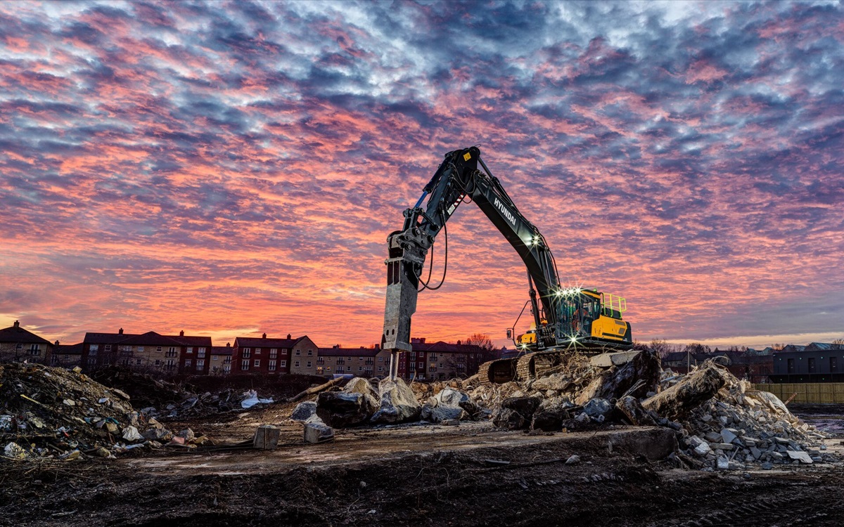 Pelle sur chenilles HD Hyundai HX480A L sur un chantier de démolition au coucher du soleil