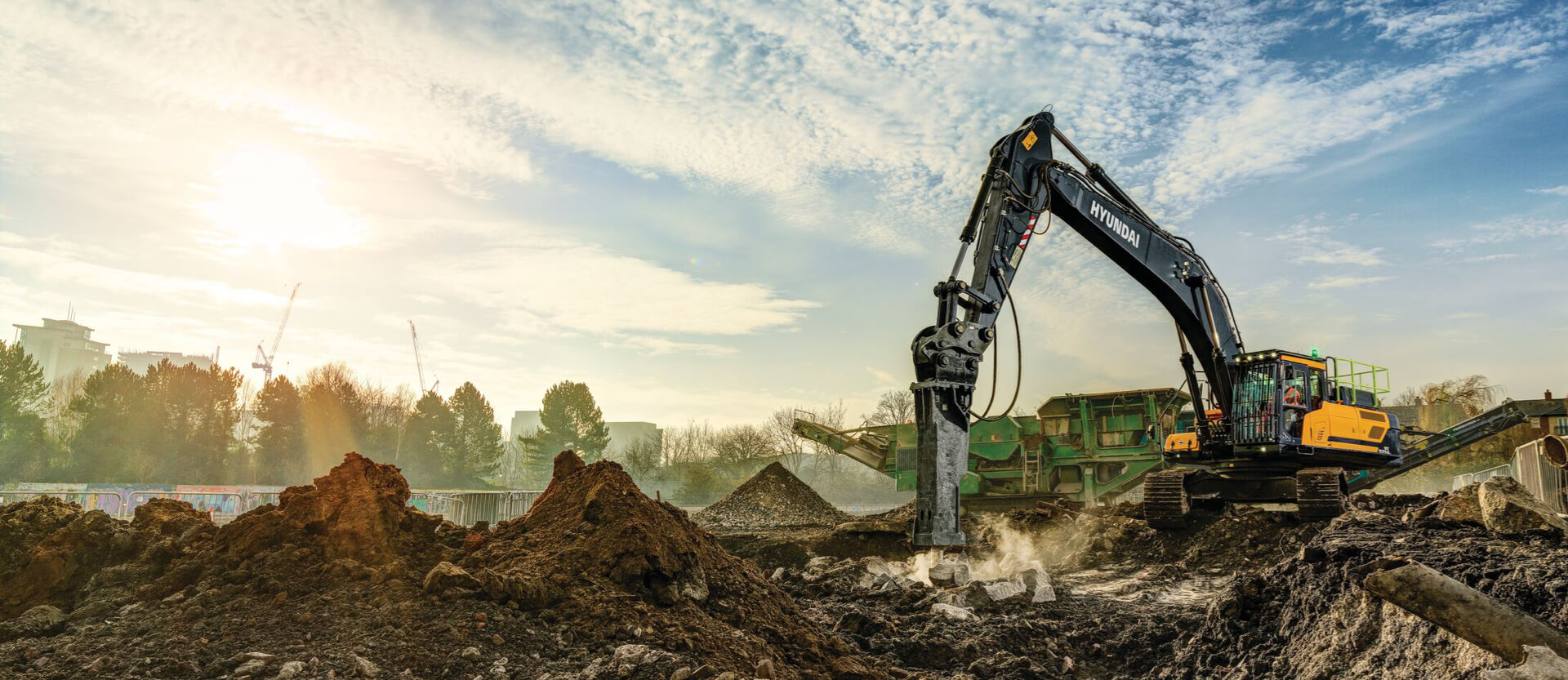 Pelle sur chenilles HD Hyundai HX520A L sur un chantier de démolition utilisant l'accessoire de brise-roche