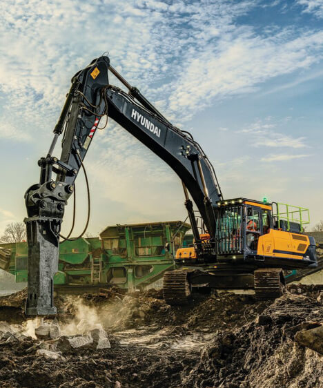 Pelle sur chenilles HD Hyundai HX520A L sur un chantier de démolition utilisant l'accessoire de brise-roche