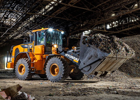 La pala gommata HD Hyundai HL955A che sposta materiale in un centro di riciclaggio