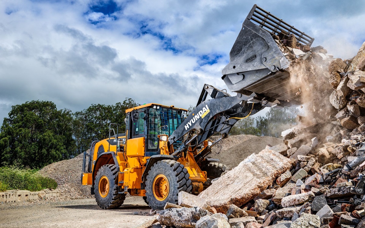 La pala gommata HD Hyundai HL955A scarica materiale su un cantiere edile