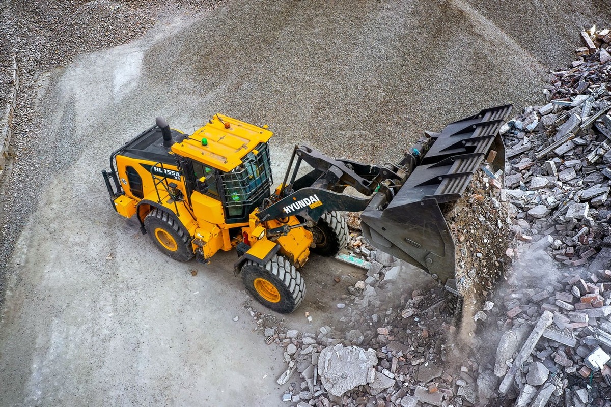 La pala gommata HD Hyundai HL955A scarica materiale su un cantiere edile