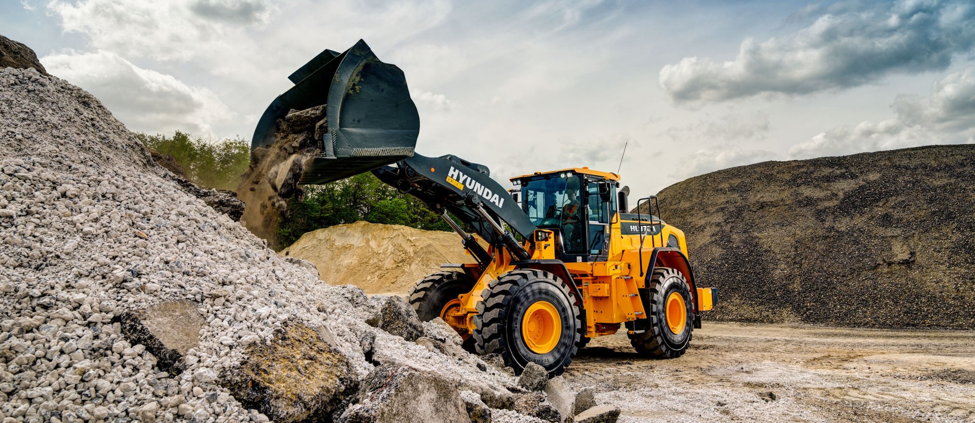 La chargeuse sur pneus HD Hyundai HL970A décharge des matériaux sur un chantier de construction